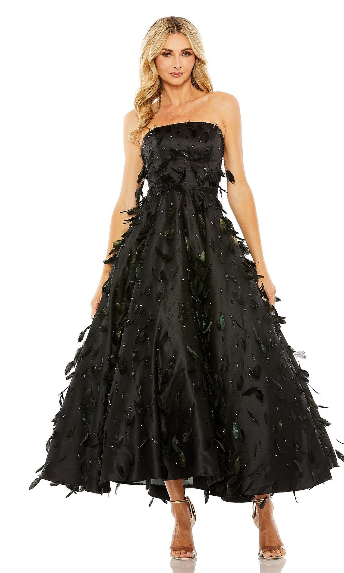 A woman wears the Strapless Midi Formal Dress: Mac Duggal 11634, a black strapless piece with leaf-like embellishments, paired with strappy high-heeled sandals.